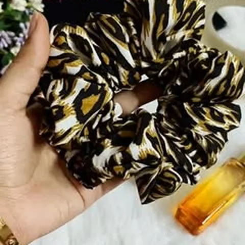 Leopard print satin scrunchie held in hand